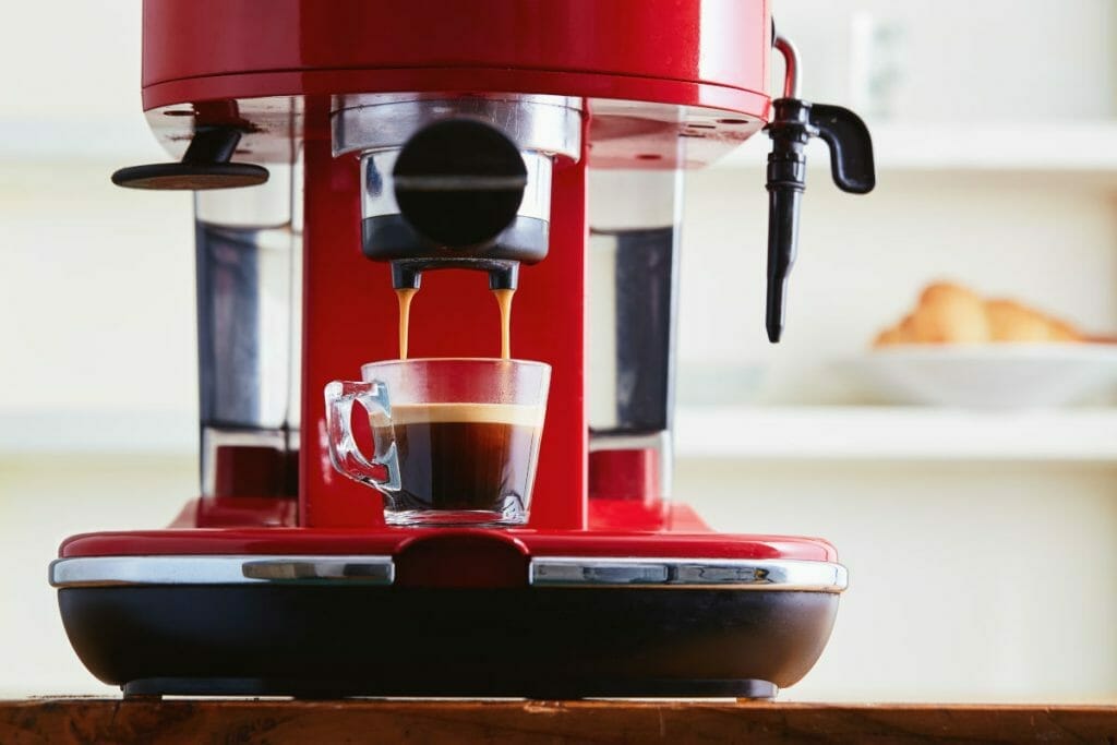 紅色濃咖啡咖啡機將濃咖啡提取到玻璃杯中的特寫鏡頭。